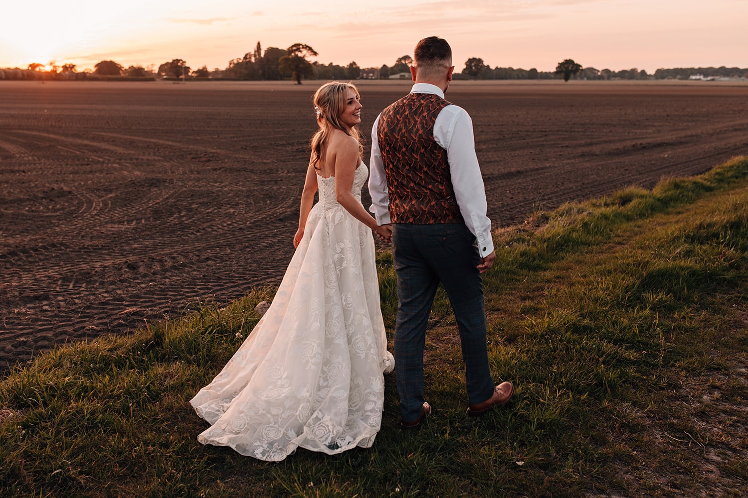 Wedding photograph of a couple walking aways from the camera into the sunset