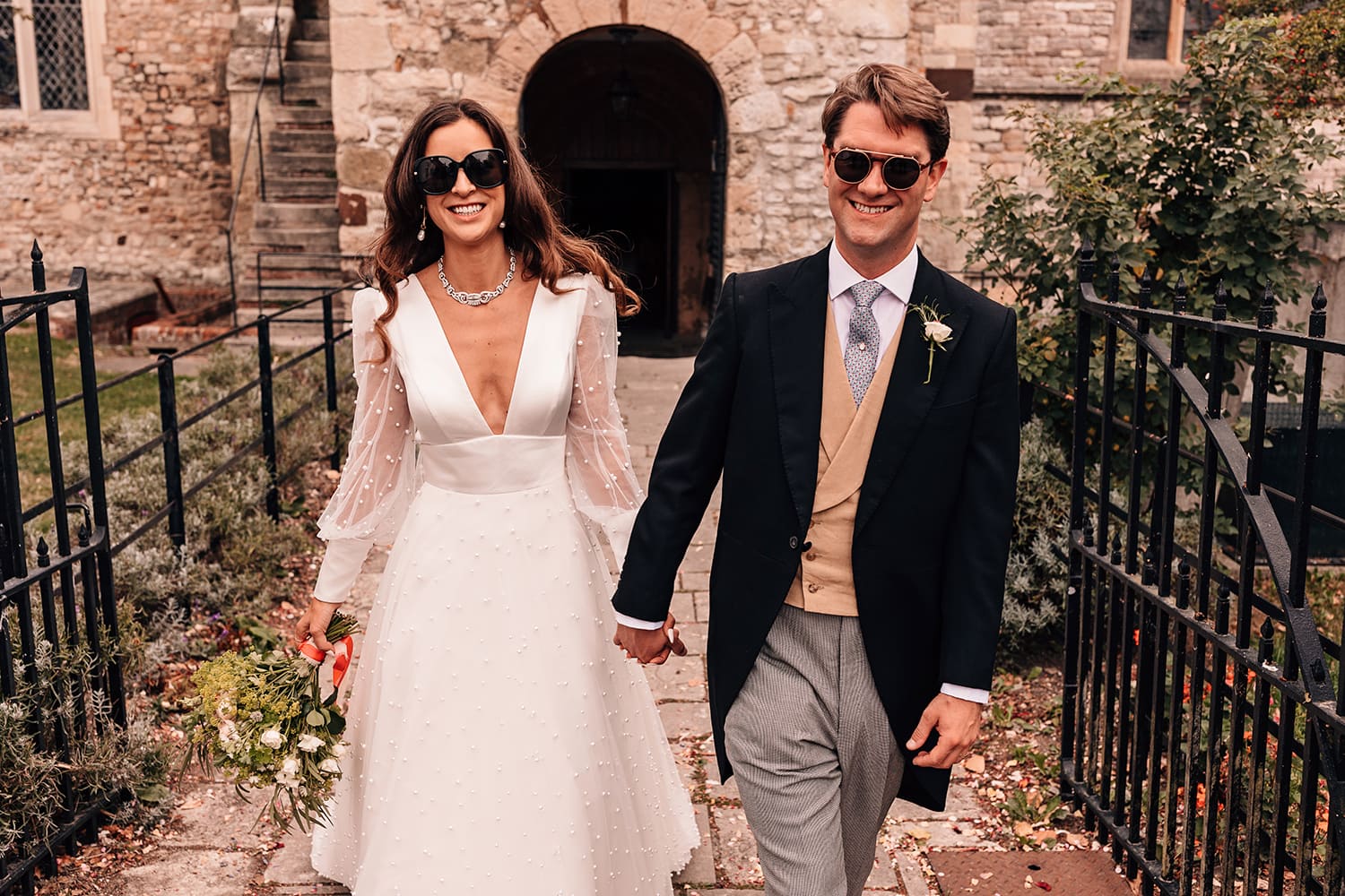 Bride and Groom wearing sunglasses walking toward the camera smiling