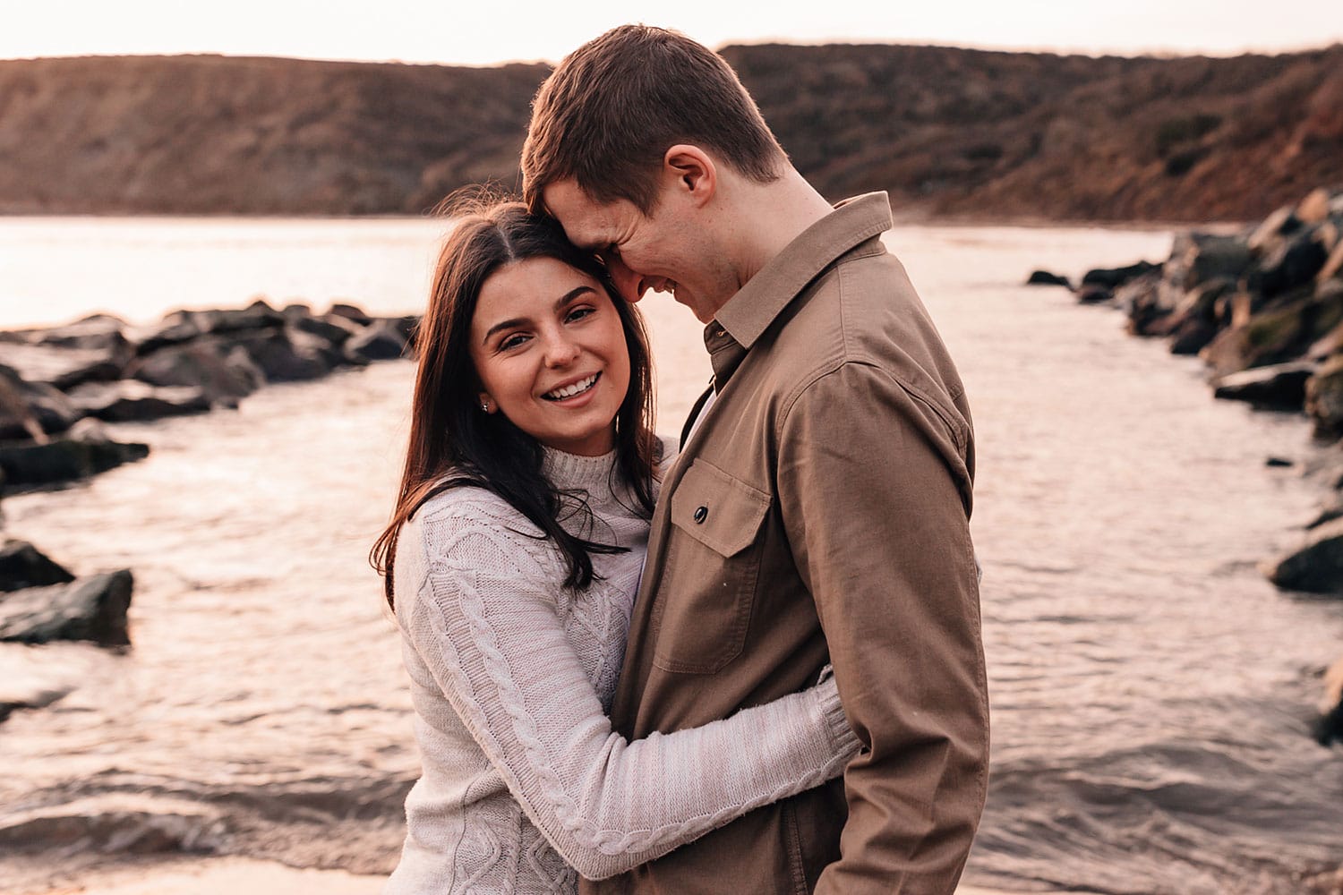 Couple cuddling on Runswick Bay beach at sunrise during their pre-wedding photo-shoot